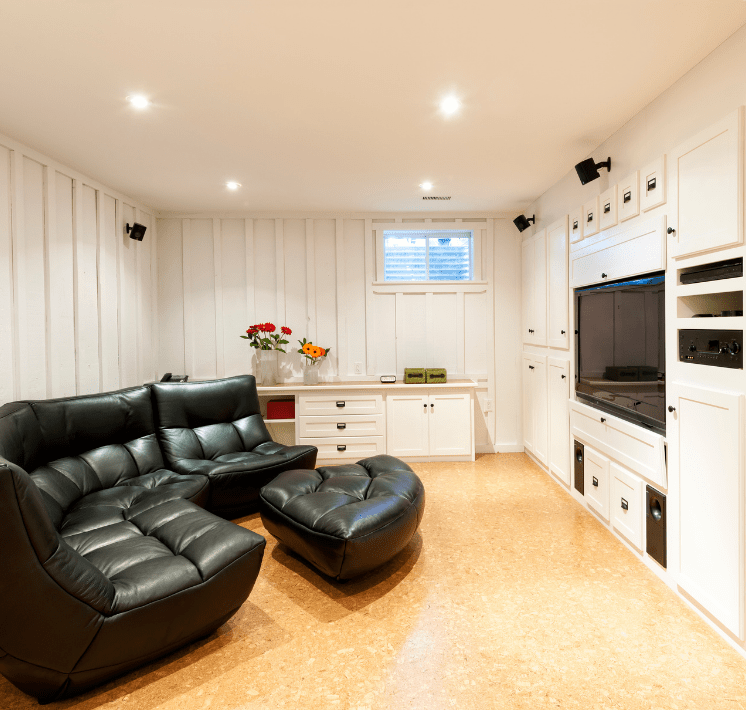 Basement with black big couch and a tv