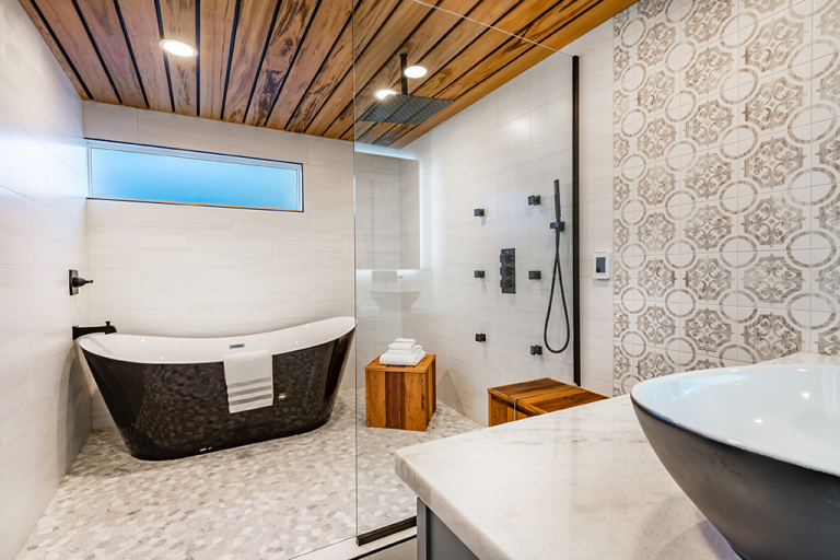 A bathroom with black bathtub, bathroom sink, and a wooden chairs, and towels