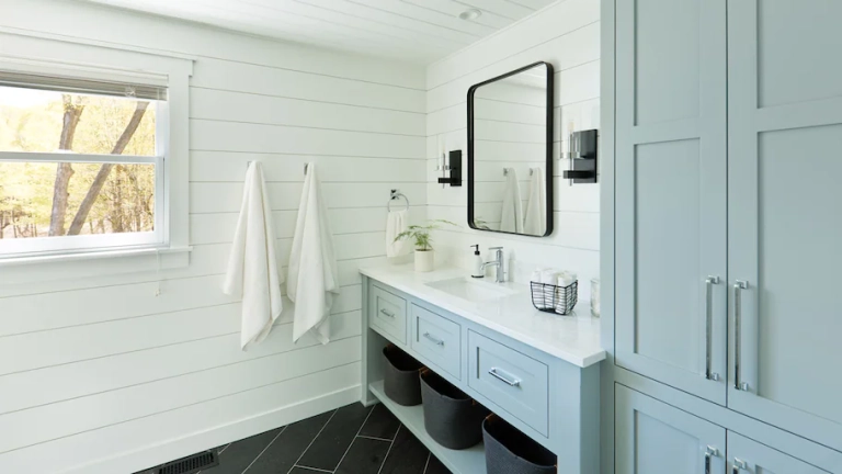 bathroom showing a black mirror, vanity, towels, baskets, and a cabinet